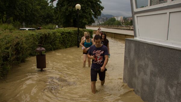 Жители идут по улице Сочи после проливного дождя