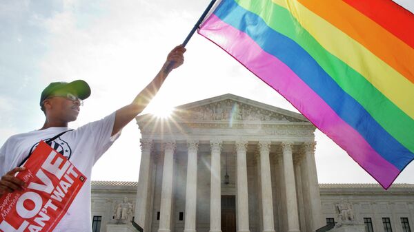 Активист держит флаг ЛГБТ у здания Верховного суда США в Вашингтоне