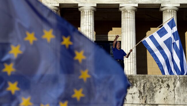 Мужчина держит флаг Греции во время проевропейской демонстрации в Афинах