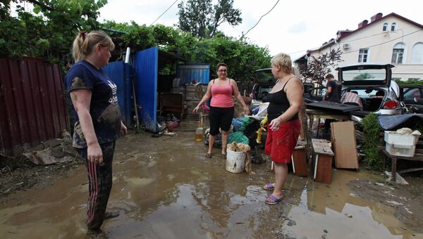 Местные жители во дворе дома, пострадавшего от подтопления после ливневых дождей в городе Сочи. Архивное фото