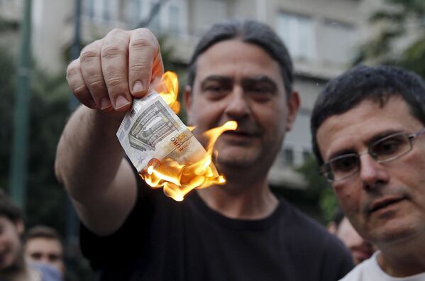 Жители сжигают евро во время акции протеста в Афинах