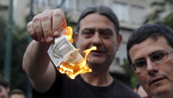 Жители сжигают евро во время акции протеста в Афинах
