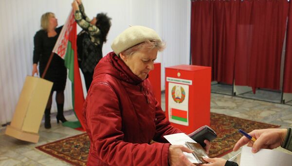 Женщина получает бюллетень для голосования на выборах на одном из избирательных участков в Минске, Белоруссия. Архивное фото