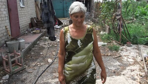 Женщина у дома, поврежденного в результате обстрела украинскими силовиками, в селе Саханка Донецкой области