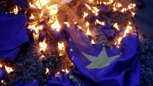 Демонстранцы жгут флаг на акции протеста против принятия проекта соглашения ЕС в Афинах