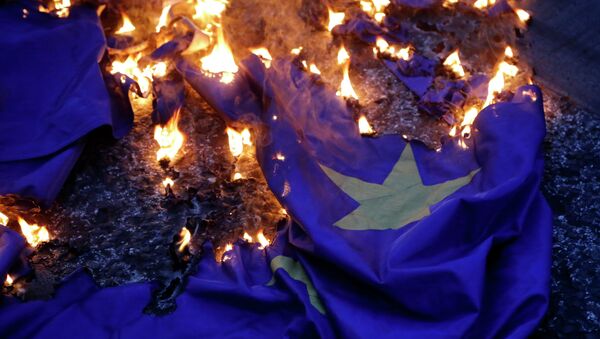 Демонстранцы жгут флаг на акции протеста против принятия проекта соглашения ЕС в Афинах. Архивное фото