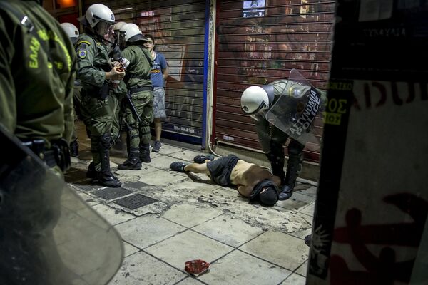 Полиция задерживает участника столкновений во время демонстрации по итогам референдума. Афины, Греция