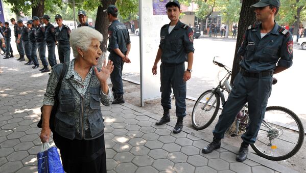 Пожилая женщина спорит с сотрудниками полиции после разгона демонстрантов в центре Еревана