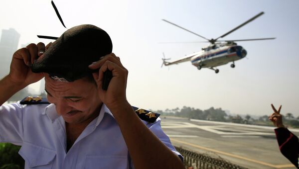 Египетский полицеский укрывается во время взлета вертолета с бывшим президентом Египта Хосни Мубараком на борту