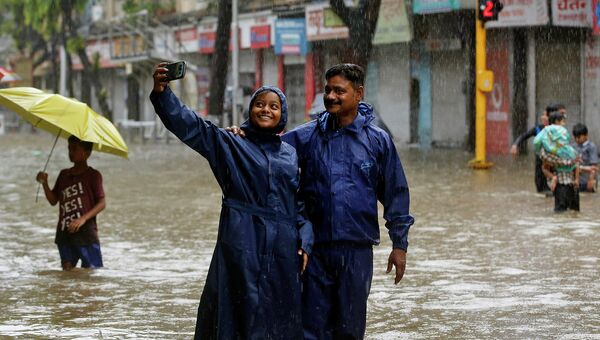 Жители Индии делают селфи на затопленных улицах во время дождя в Мумбаи. 2015 год