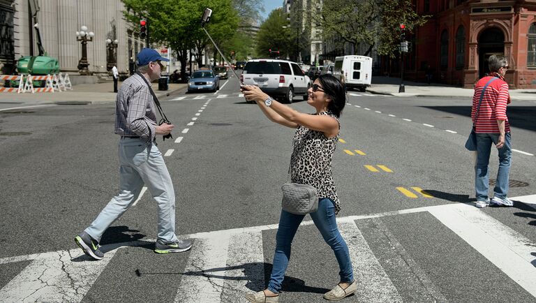 Девушка делает селлфи во время пересечения проезжей части в Вашингтоне, США. 2015 год