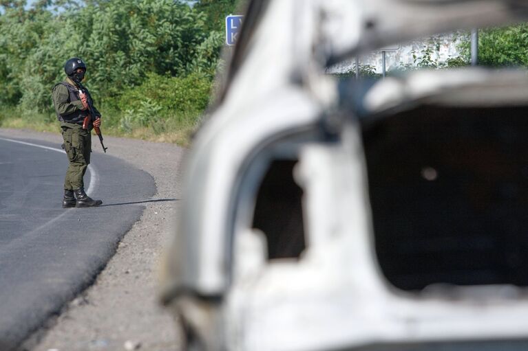 Сотрудник полиции возле сгоревшего автомобиля в Мукачево, Украина