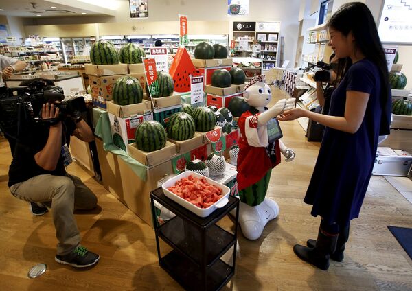 Робот Pepper в роли менеджера общается с клиентом в магазине Токио, Япония. Июль 2015