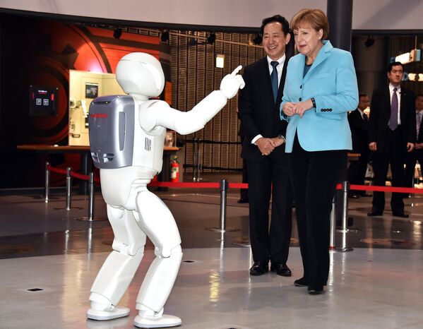 Канцлер Германии Ангела Меркель общается с роботом Asimo в музее Токио, Япония. Март 2015