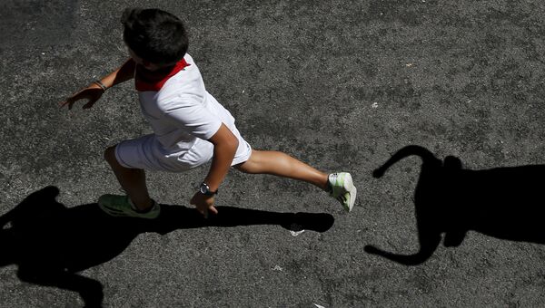 Мальчик убегает от игрушечного быка во время фестиваля Сан-Фермин в Памплоне. Испания, июль 2015