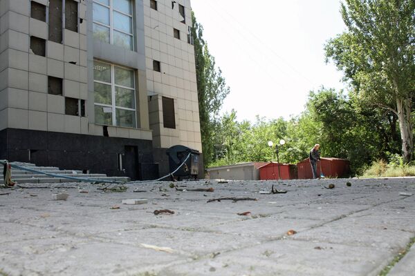 Мужчина убирает мусор у здания, поврежденного в результате ночного обстрела Донецка