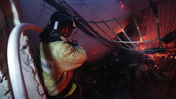 Пожарный тушит здание, загоревшееся в результате обстрела Донецка