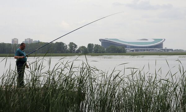Мужчина рыбачит у стадиона Арена в Казани. Июль 2015