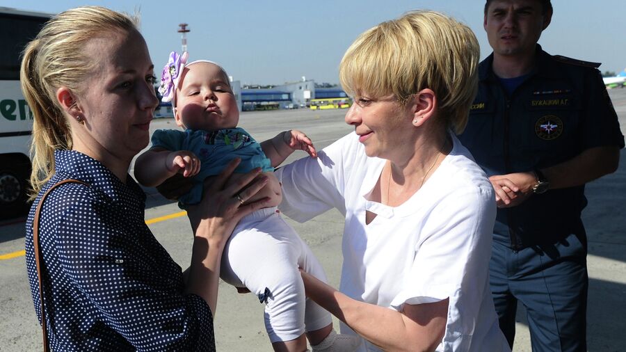 Елизавета Глинка помогает женщине с ребенком во время посадки на спецборт МЧС РФ в аэропорту Ростова-на-Дону перед отправкой детей из Донбасса для лечения в Москву