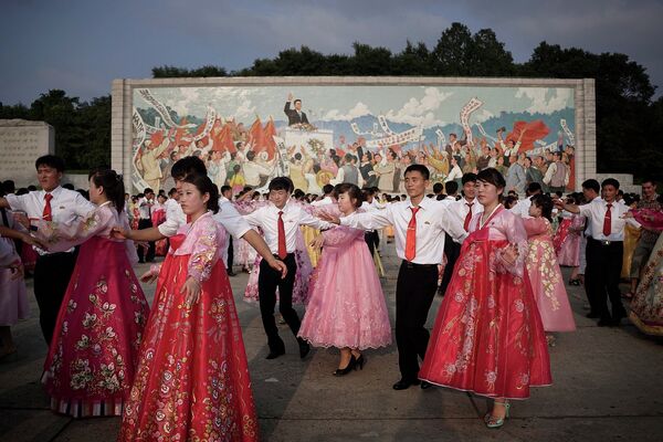 Студенты танцуют на фоне изображения Ким Ир Сена в Пхеньяне, КНДР