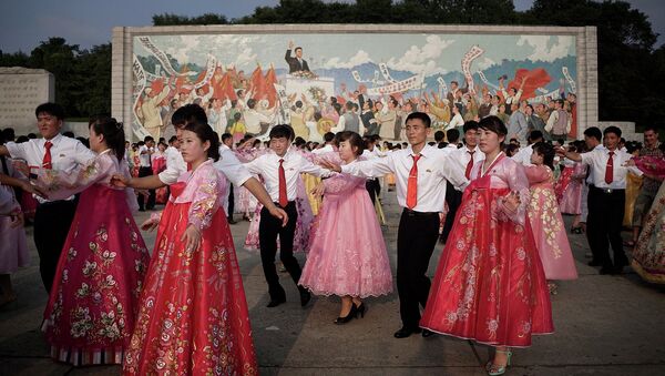 Студенты танцуют на фоне изображения Ким Ир Сена в Пхеньяне, КНДР. Архивное фото