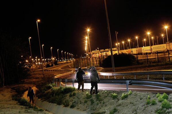 Мигранты идут вдоль дороги недалеко от Евротуннеля