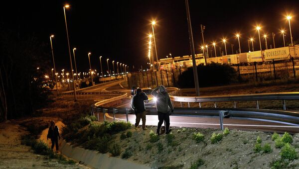 Мигранты идут вдоль дороги недалеко от Евротуннеля. Архивное фото