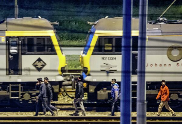 Мигранты идут вдоль железнодорожных путей в терминале Евротуннеля