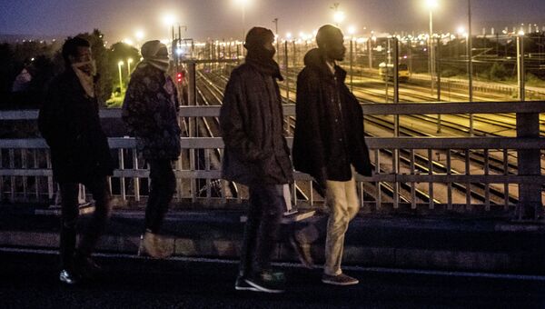 Мигранты пересекают мост над железнодорожными путями Евротуннеля в городе Кале. Архивное фото