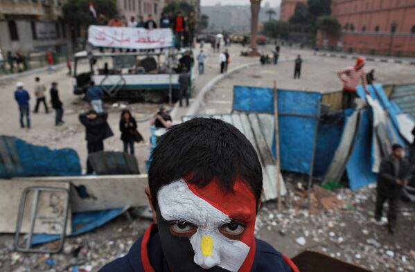 Сторонник оппозиции с лицом, раскрашенным в цвета государственного флага Египта, на баррикадах на площади Тахрир в Каире
