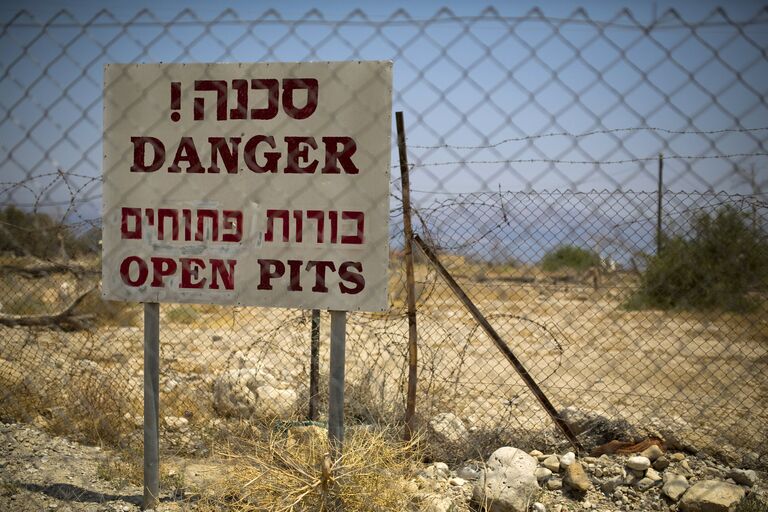Предупреждающая об опасности табличка на оставленной территории возле Мертвого моря