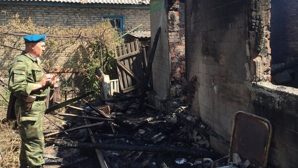 Ополченец осматривает дом, пострадавший в результате обстрела украинскими силовиками, в Горловке Донецкой области
