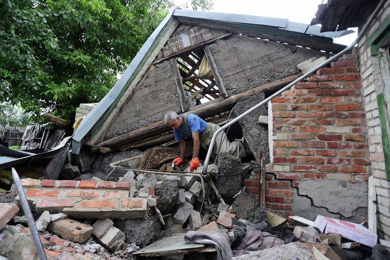 Спасатель возле разрушенного в результате обстрела дома в поселке Гольмовский Донецкой области