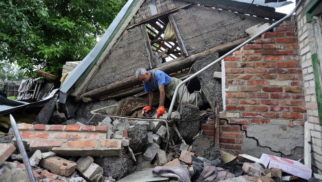 Спасатель возле разрушенного в результате обстрела дома в поселке Гольмовский Донецкой области