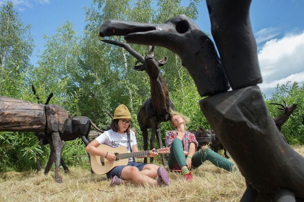Посетители у деревянных скульптур оленей на фестивале ландшафтных объектов Архстояние