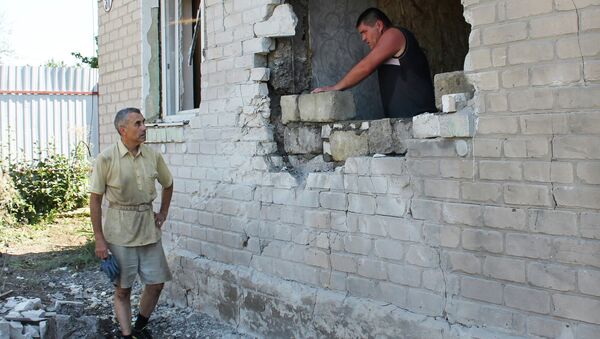 Мужчина ремонтирует стену жилого дома в Горловке после обстрела. Архивное фото