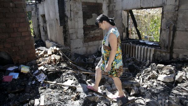 Женщина ходит по обломкам своего дома, разрушенного в результате обстрела Донецка 2 августа 2015