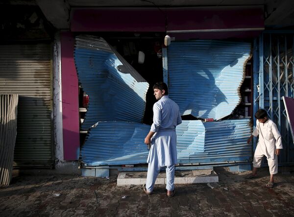 Афганец стоит рядом с поврежденным в результате взрыва магазином в Кабуле