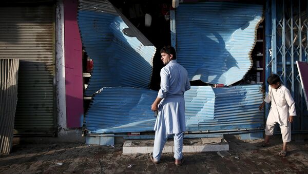 Афганец стоит рядом с поврежденным в результате взрыва магазином в Кабуле