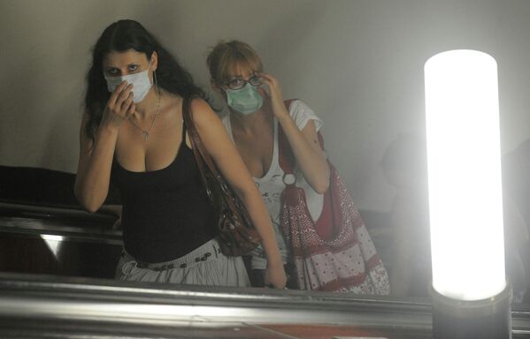 Пассажиры на эскалаторе метрополитена во время смога в Москве