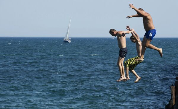 Мужчины прыгают в Черное море в городе Евпатория
