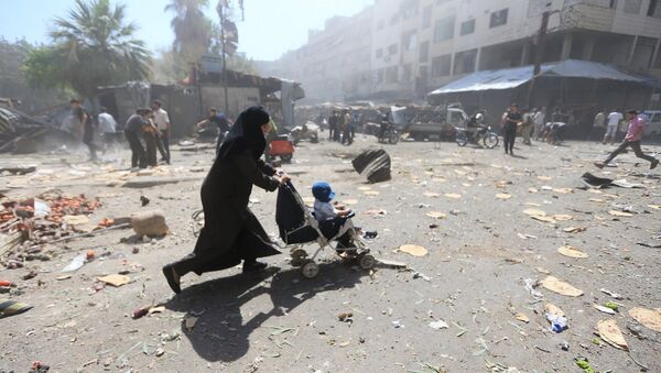 Женщина с ребенком на улице Дамаска, подвергшейся авиаударам. 12 августа 2015