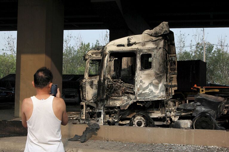 Поврежденный автомобиль в результате взрывов на складе опасных веществ в промышленном городе Тяньцзинь в Китае