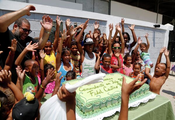 Скульптор Алексис Лейва позирует с детьми возле праздничного торта в честь дня рождения Фиделя Кастро