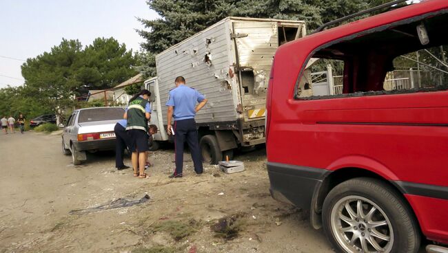 Поврежденные в результате обстрела автомобили на улице поселка Сартан недалеко от Мариуполя