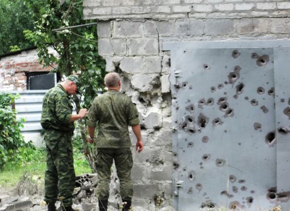 Сотрудники МЧС у ворот, поврежденных осколками в результате обстрела Донецка