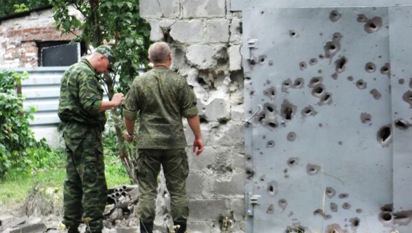 Сотрудники МЧС у ворот, поврежденных осколками в результате обстрела Донецка. Архивное фото