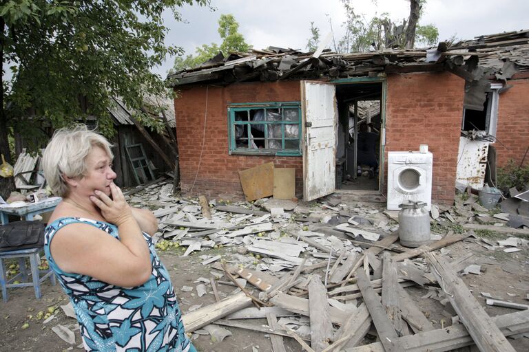 Женщина возле разрушенного во время обстрела дома в Донецке