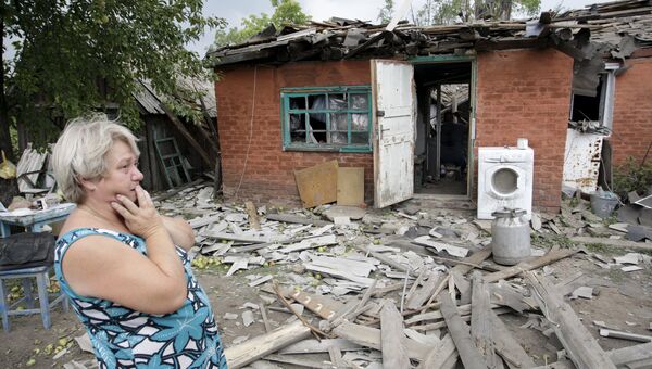 Женщина возле разрушенного во время обстрела дома в Донецке