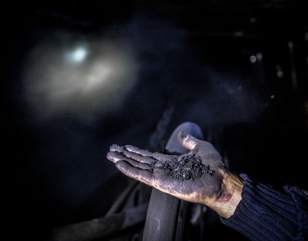 Шахтер показывает уголь на шахте Глубокая в Шахтерске